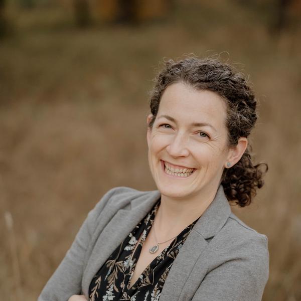 Smiling woman in a grey blazer.