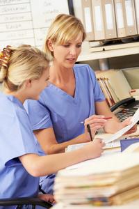 Two nursing unit assistants looking at files.
