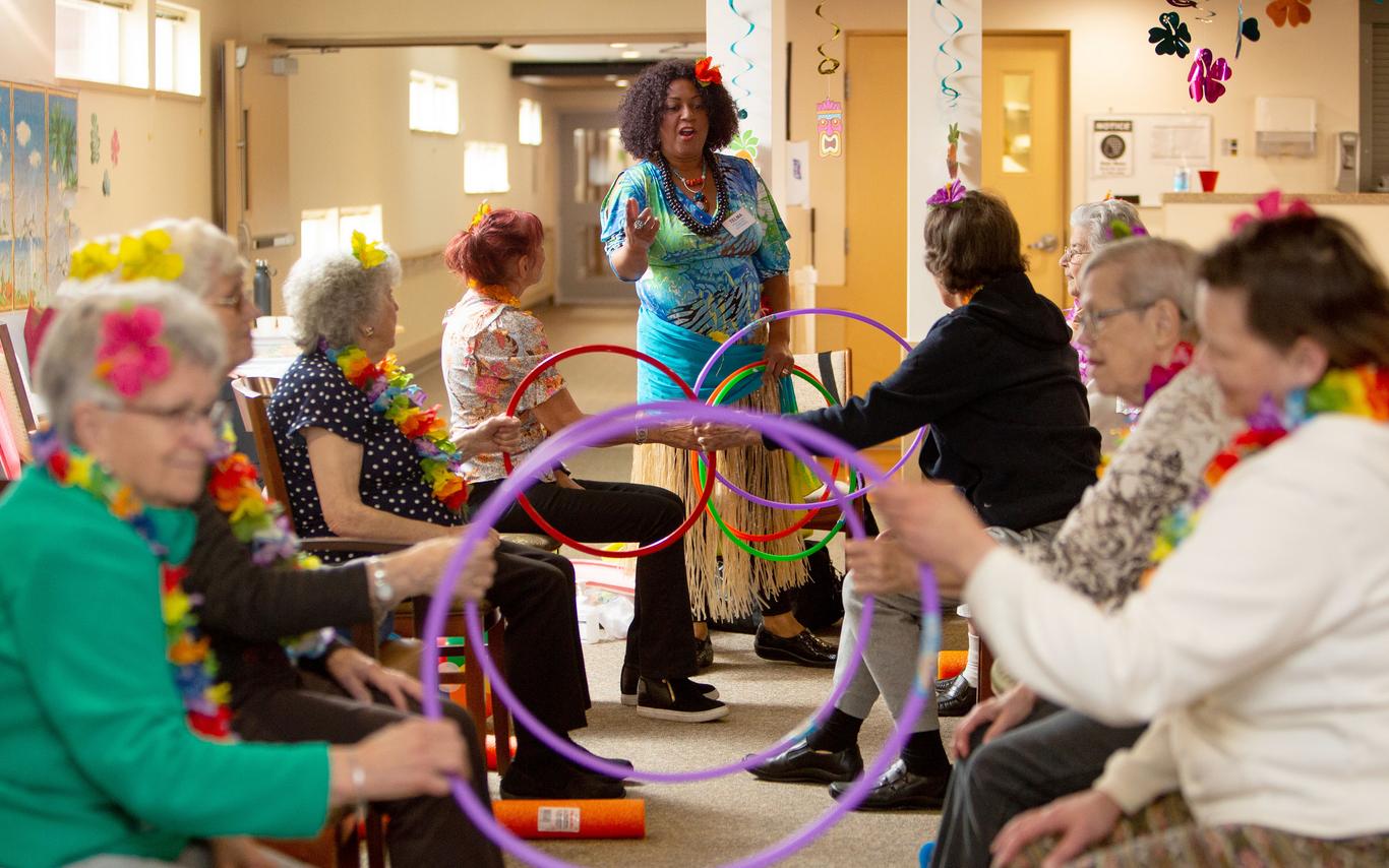 A woman guiding older adults in a game involving hoola hoops